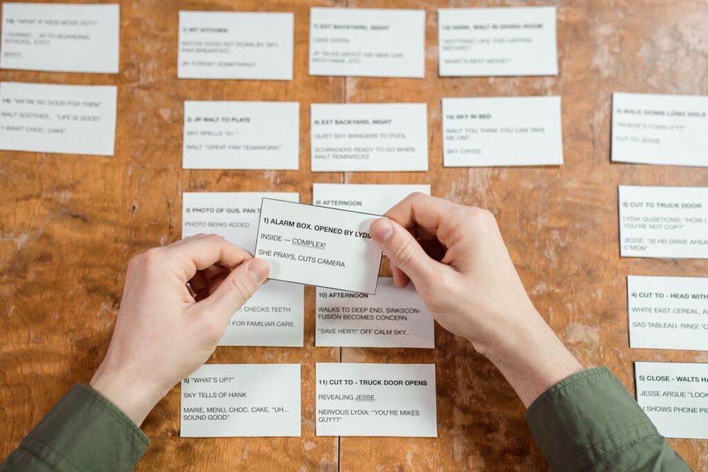 Hands arranging rows of typed index cards on a wooden table to plan a story