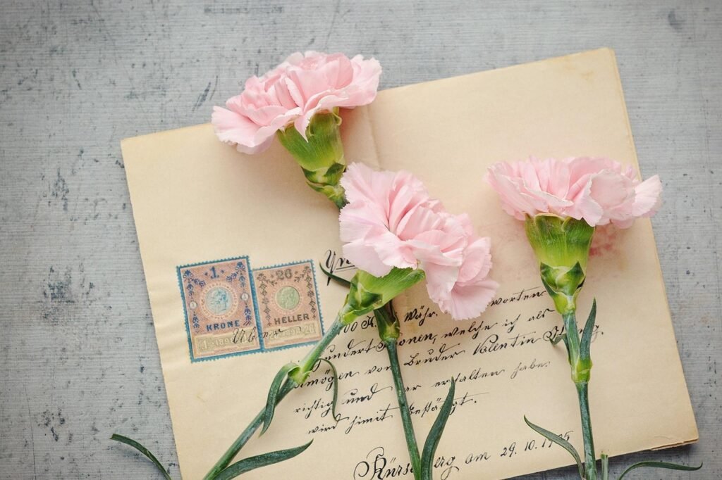 Vintage envelope with postage stamps and handwriting under three pink carnations