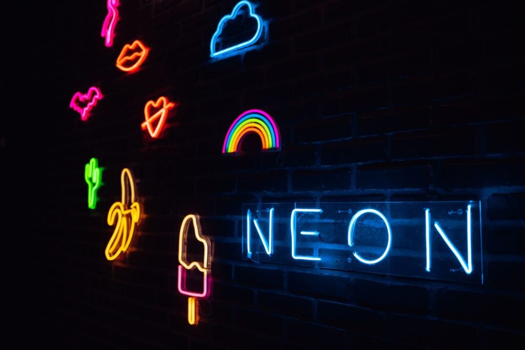Colorful glowing neon tubes shaped like hearts, a rainbow, a cloud, and the word neon