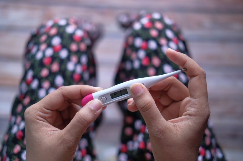 Close-up of hands holding a digital thermometer against a blurred background.