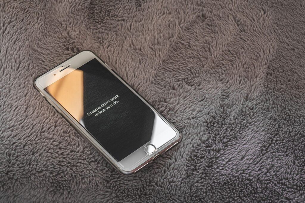 A white smartphone lying face up on a thick grey shaggy rug