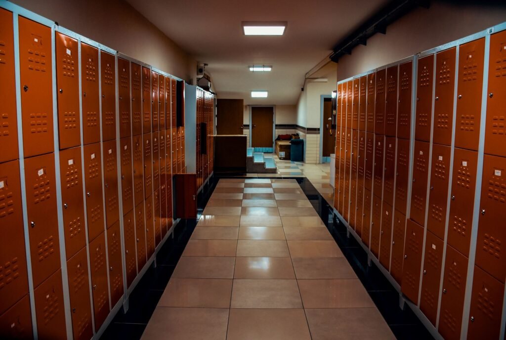 A corridor lined on both sides with tall orange metal lockers above a tiled floor