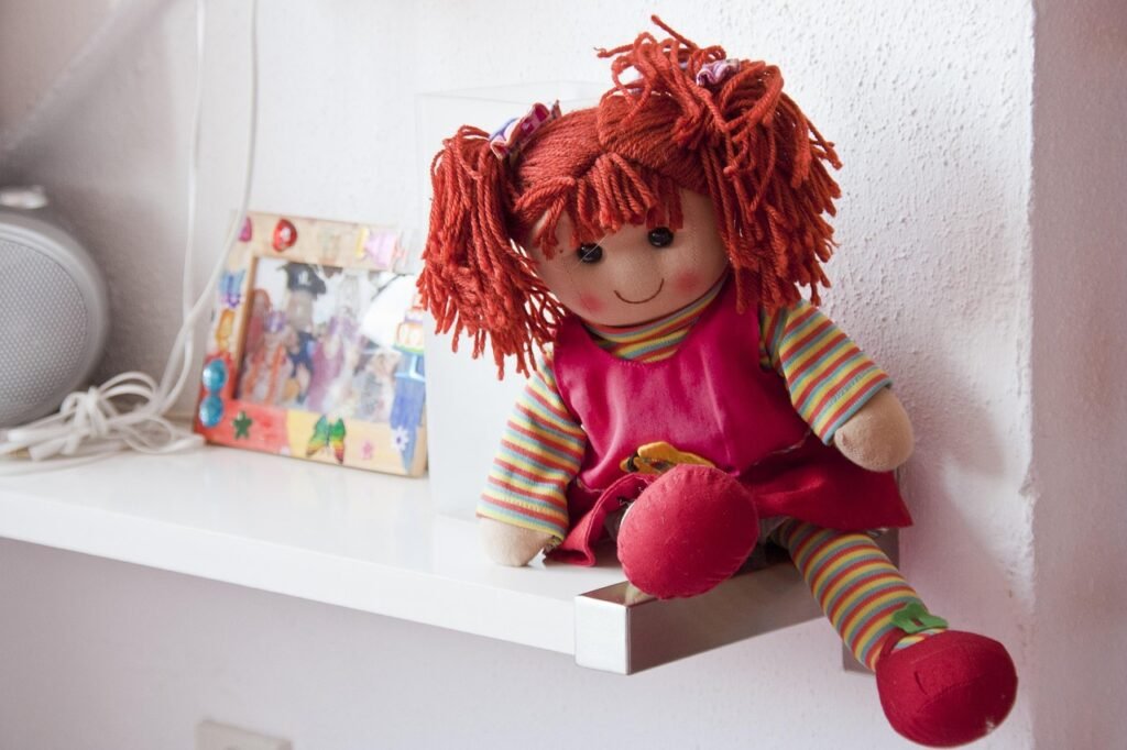 A rag doll with yarn hair sitting on a shelf