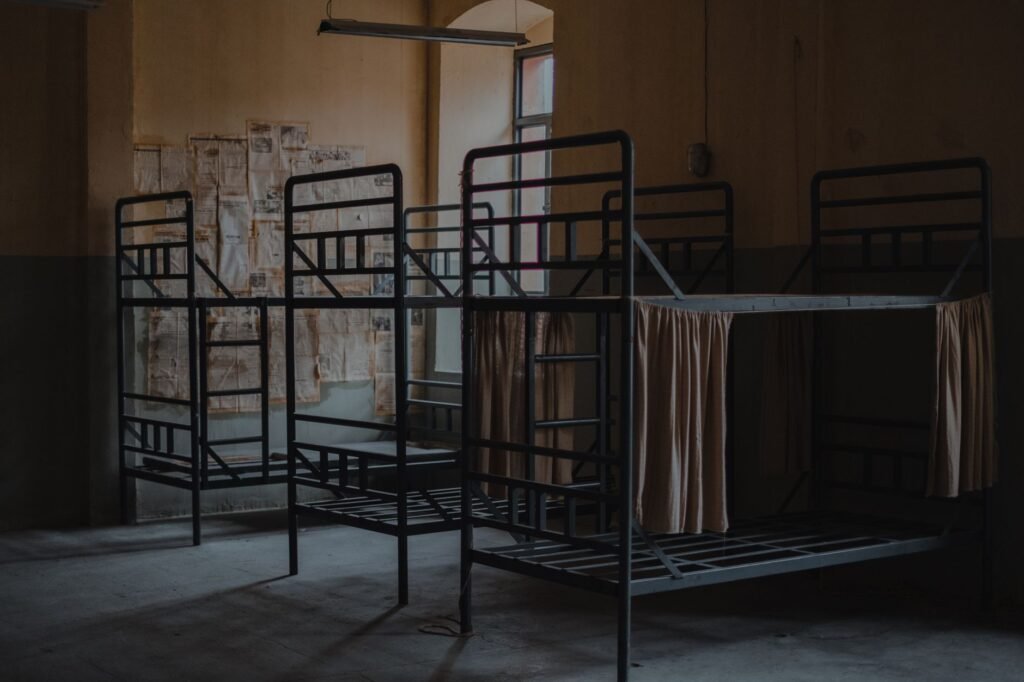 Black metal bunk bed frames with bare mattress bases in a dim empty room