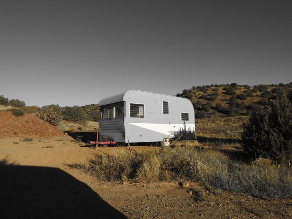 A vintage caravan parked in a serene desert setting under clear skies, perfect for travel enthusiasts