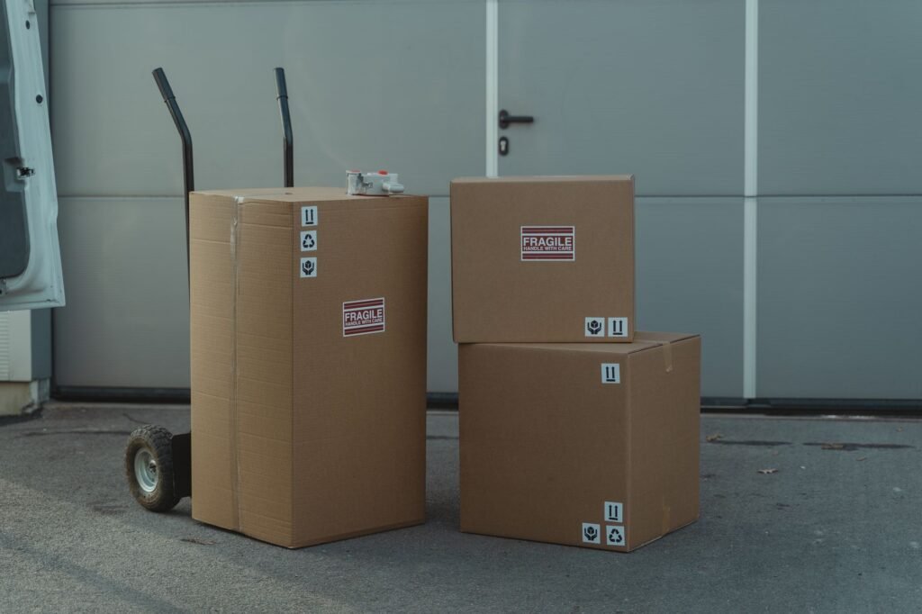 Three cardboard boxes on a dolly, ready for shipping outside a warehouse