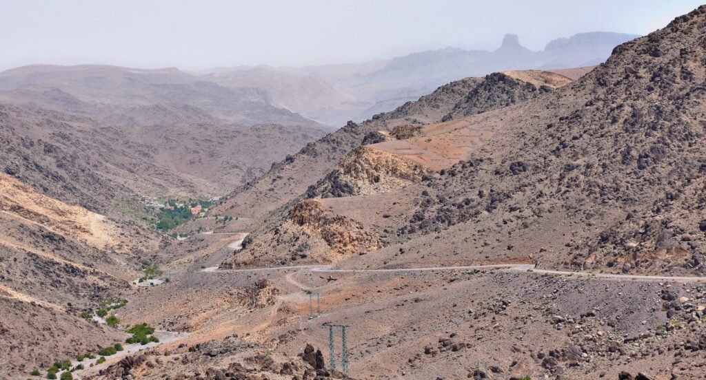 Vast rocky landscape of Irherm, Morocco with winding roads and distant mountains