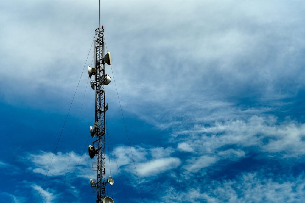 A tall guyed steel radio mast with support cables against open sky