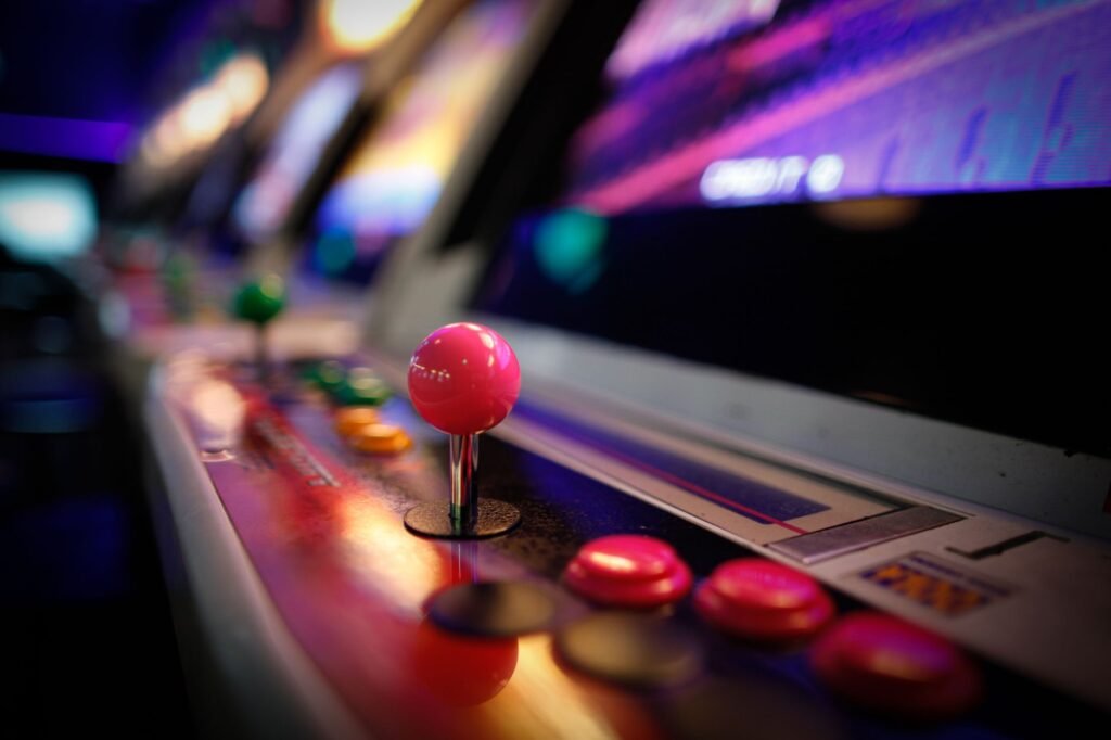 Close-up of a colorful vintage arcade machine with glowing joysticks and buttons in a dimly lit game room