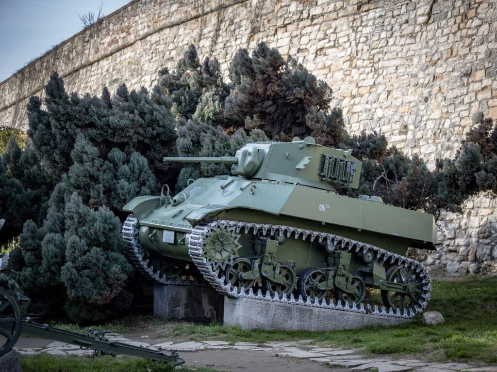 World War II era tank on display near a stone wall in a public setting