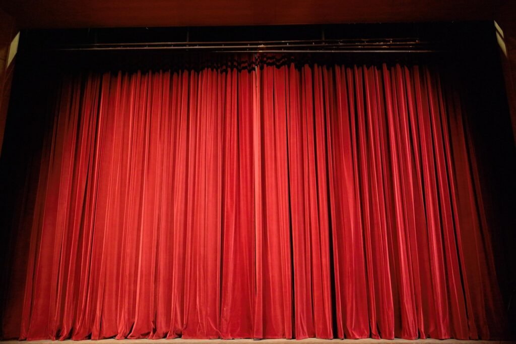 An empty theater stage with heavy red velvet curtains