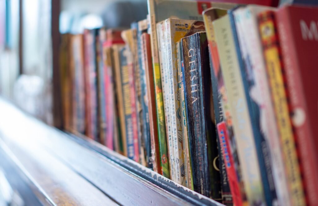 A close-up view of various colorful books lined up on a rustic wooden shelf indoors