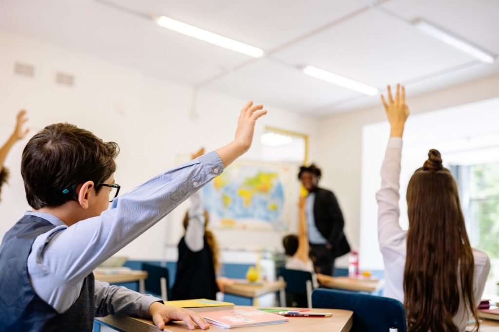 Enthusiastic students participating in a classroom, raising hands to answer teacher's question