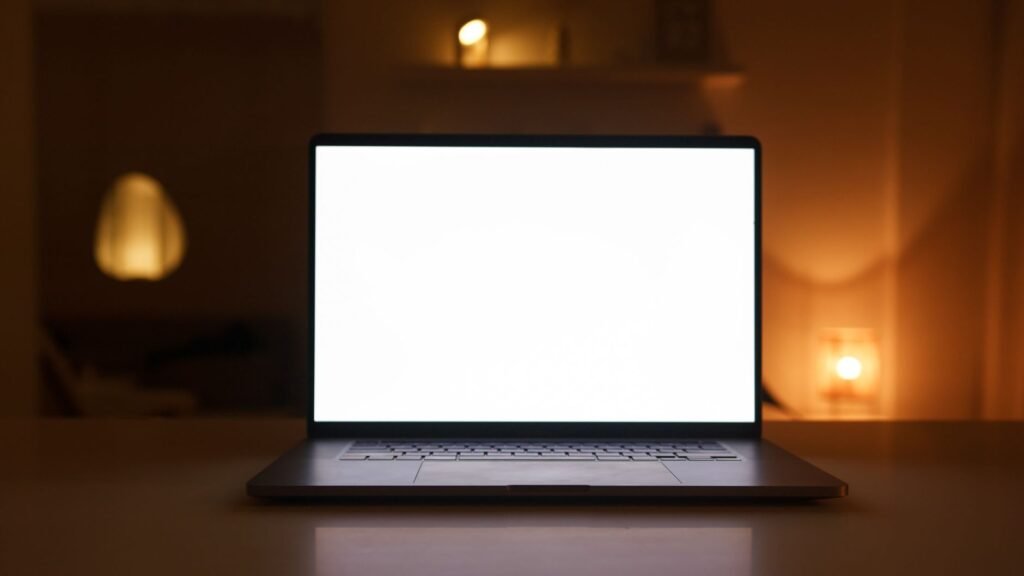 Laptop with a blank white screen on a desk in a warmly lit room, perfect for mockups or presentations