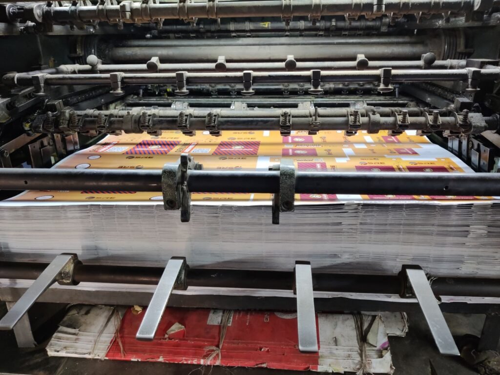 Close-up of an industrial printing machine processing paper sheets in a factory setting