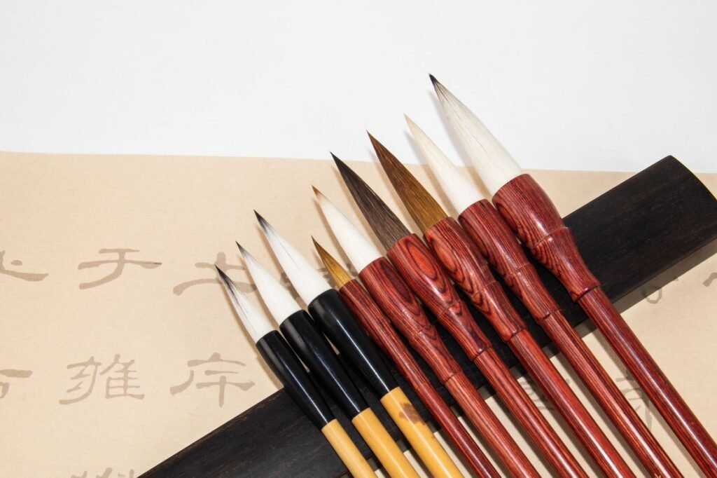 From above of different calligraphy brush pens with pointed tips and bamboo shafts on white table