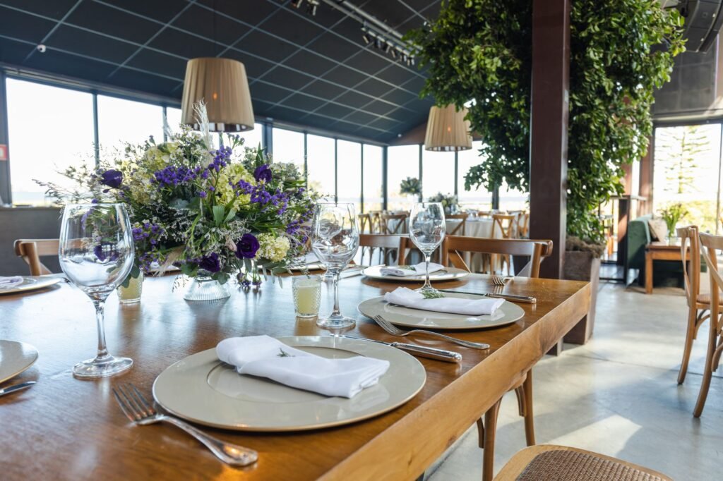 A beautifully arranged wedding table setting in a well-lit reception hall with floral centerpieces