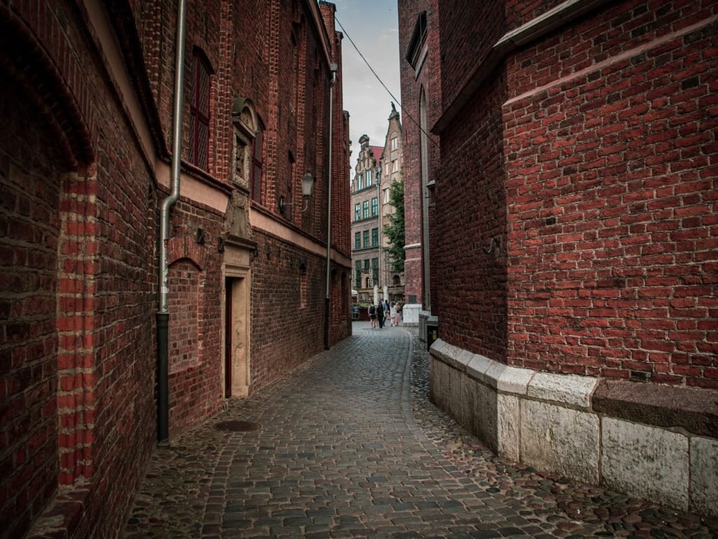 Explore a quaint cobblestone alleyway surrounded by historic brick buildings on a quiet day