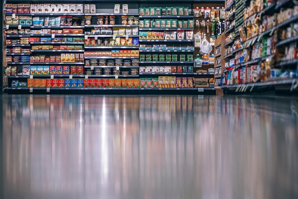 An empty supermarket aisle with a wide polished floor and packed shelves behind