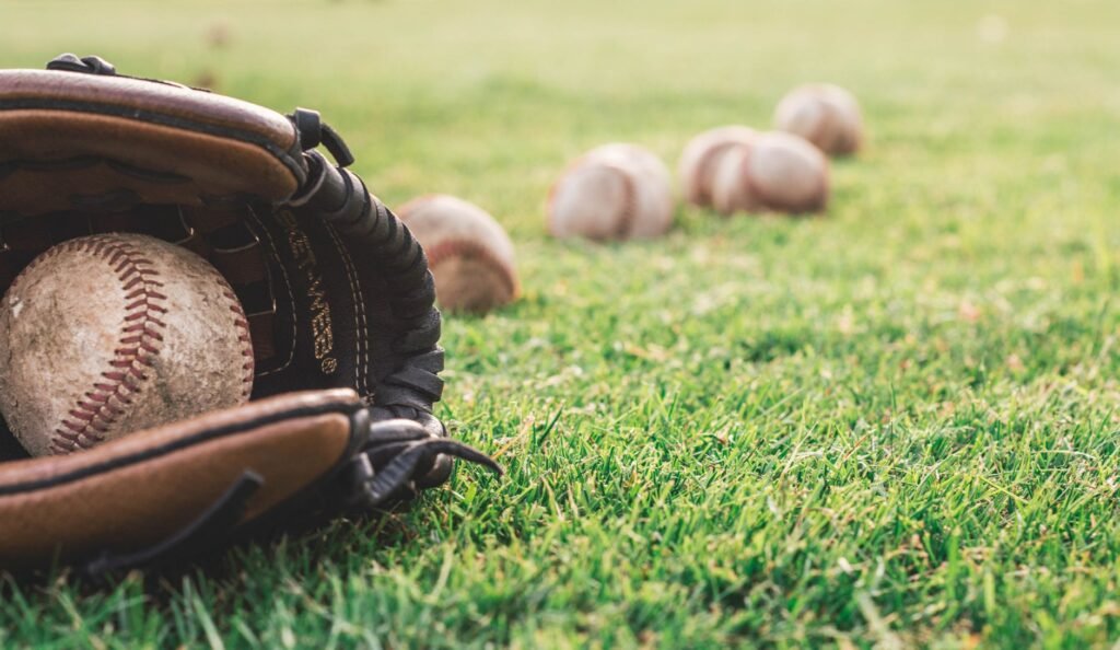 A close-up of a baseball glove with balls on a green field, symbolizing outdoor sports