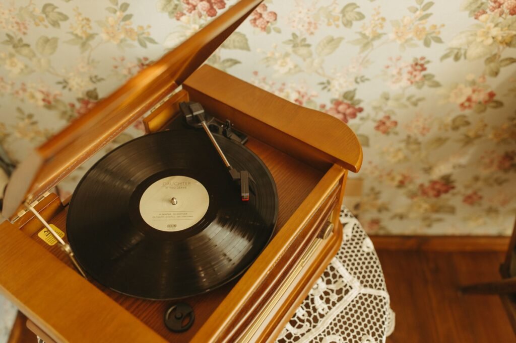 A vintage turntable playing a vinyl record in a cozy, retro interior with floral wallpaper
