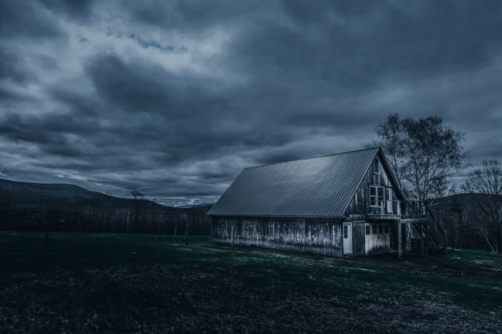 Weathered wooden cottage located against gray overcast sky in evening in countryside
