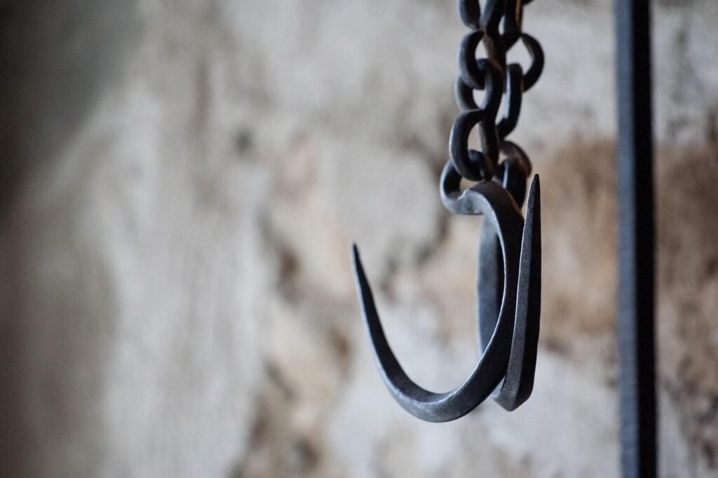 A rusting metal hook hanging from a chain