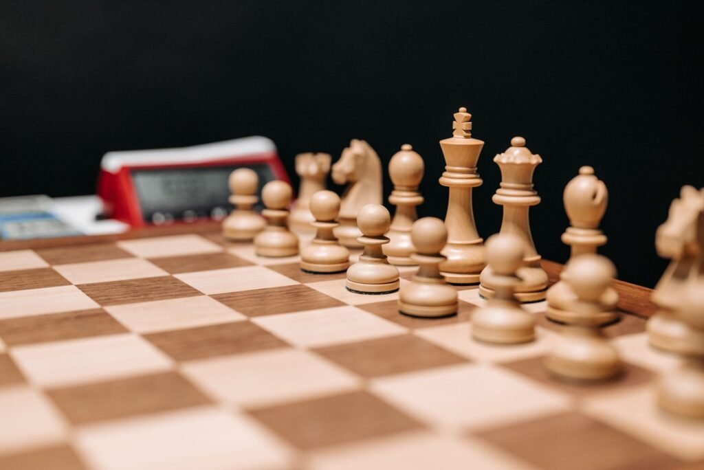 Detailed view of wooden chess pieces on a board with a chess clock in the background