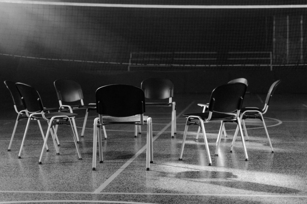Empty chairs arranged in a circle on a polished indoor sports hall floor