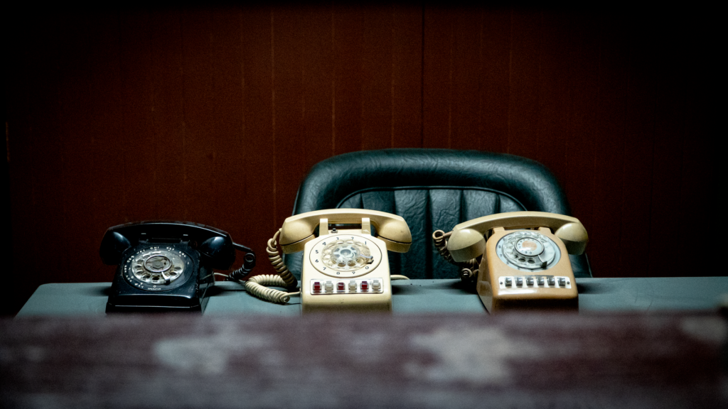 Three vintage rotary phones on an empty desk evoke nostalgia and classic communication