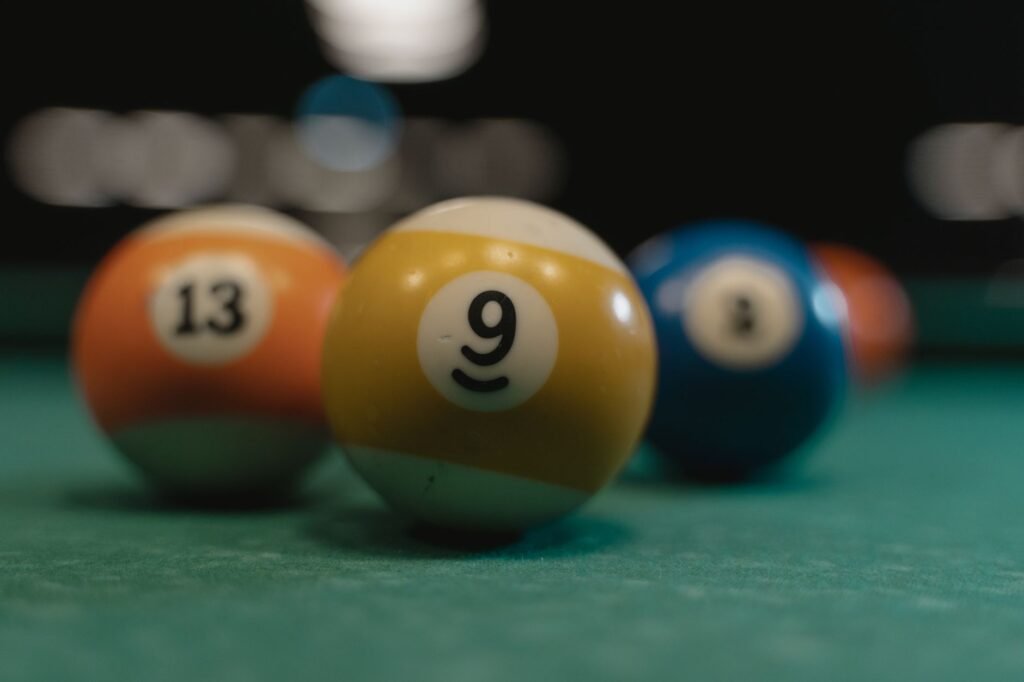 Close view of numbered billiard balls touching on a green felt table