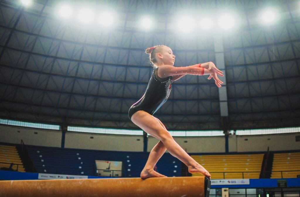 A young gymnast performing a routine on the balance beam indoors during a competition