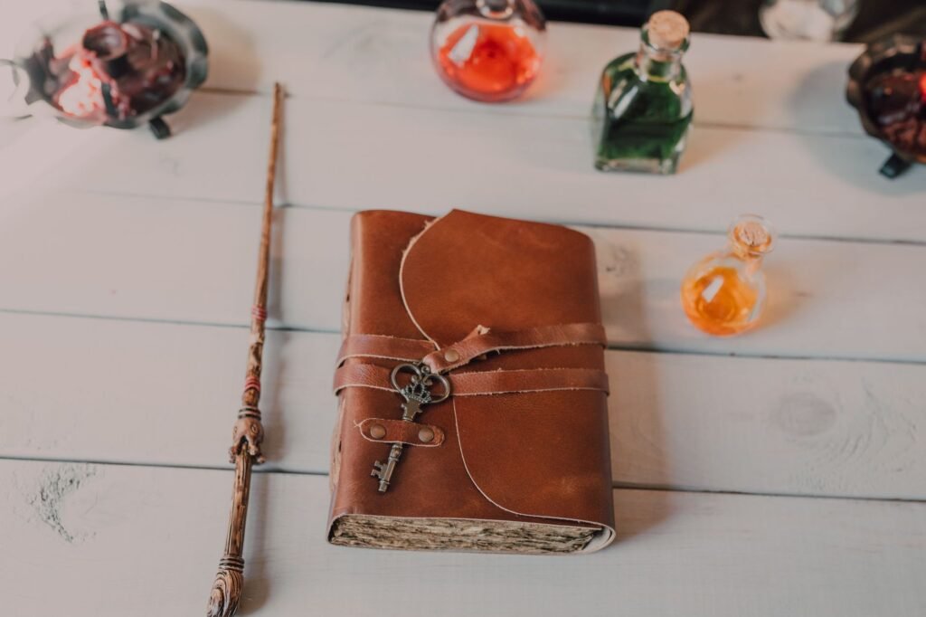 Brown leather wrap journal with a small key charm on a white wooden table near glass bottles