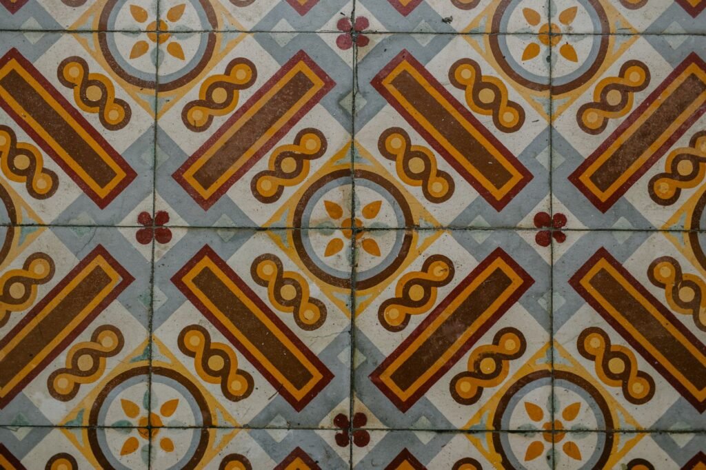 Patterned floor tiles with orange, yellow, and blue geometric shapes and small floral accents