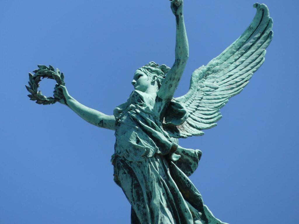 Sculpture of Winged Victory with laurel wreath against a clear blue sky in Brussels