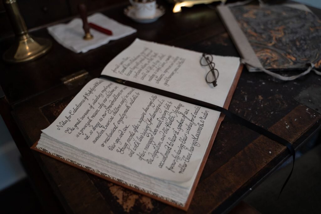 A vintage notebook with calligraphy text and eyeglasses on a wooden desk, creating a nostalgic scene