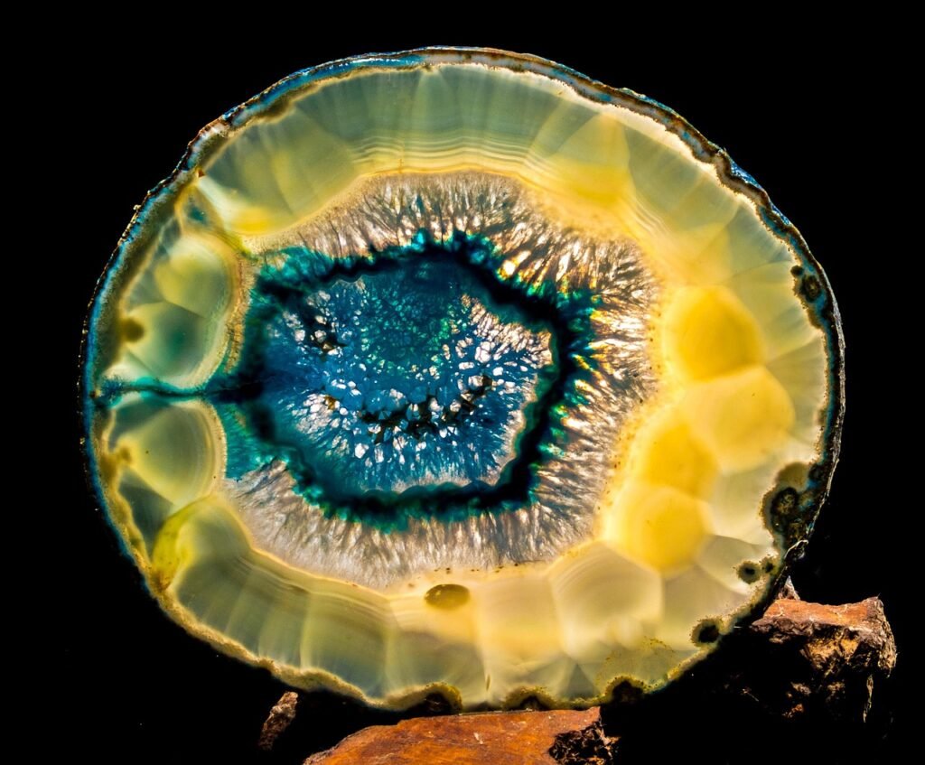 Polished agate slice with concentric yellow bands around a sparkling blue crystal center