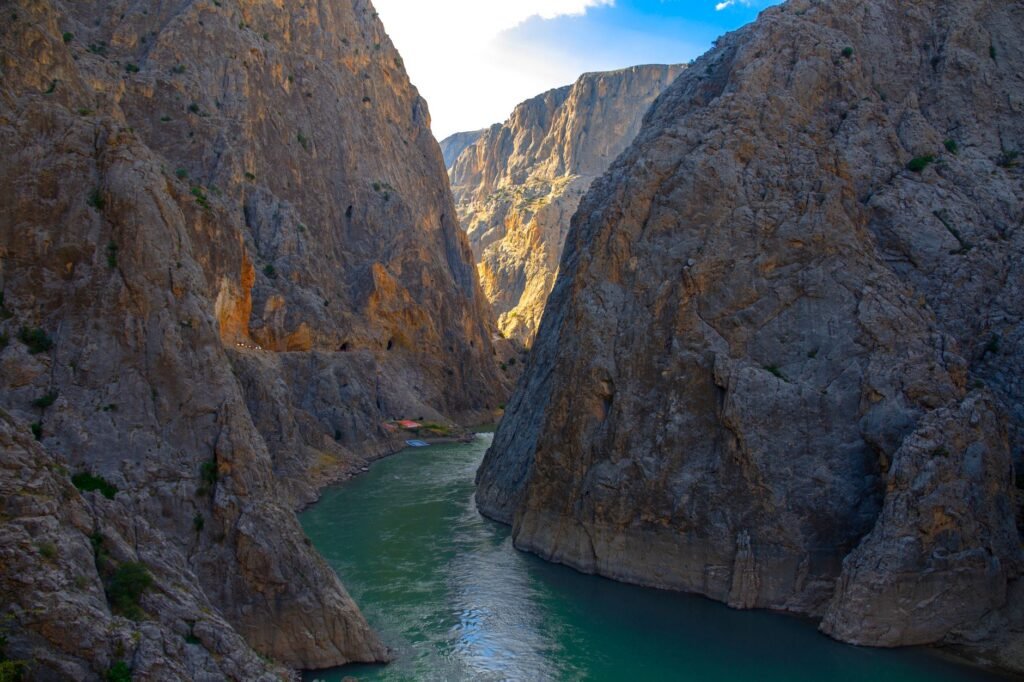 Steep rocky cliffs rising on both sides of a narrow gorge with a green river below