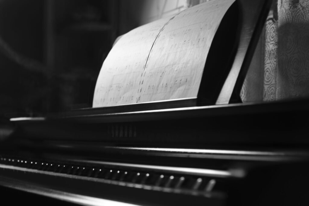 Sheet music propped open on the music rest of a piano in black and white