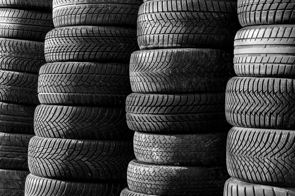 Tall stacks of worn black tires with deep tread packed side by side