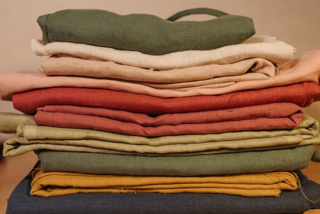 Stack of folded fabric pieces in earthy tones of green, rust, beige, and mustard