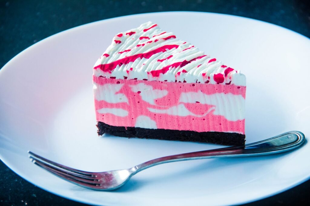 Single slice of pink and white layered cake with a fork on a white plate