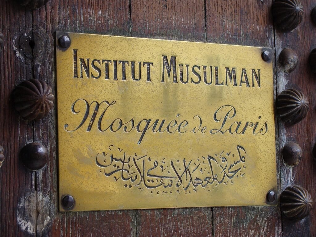 Engraved brass plaque with lettering in two scripts mounted on a studded wooden door
