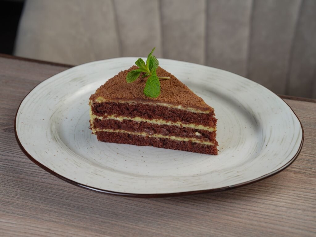 A tempting chocolate layer cake slice with mint garnish on a white plate