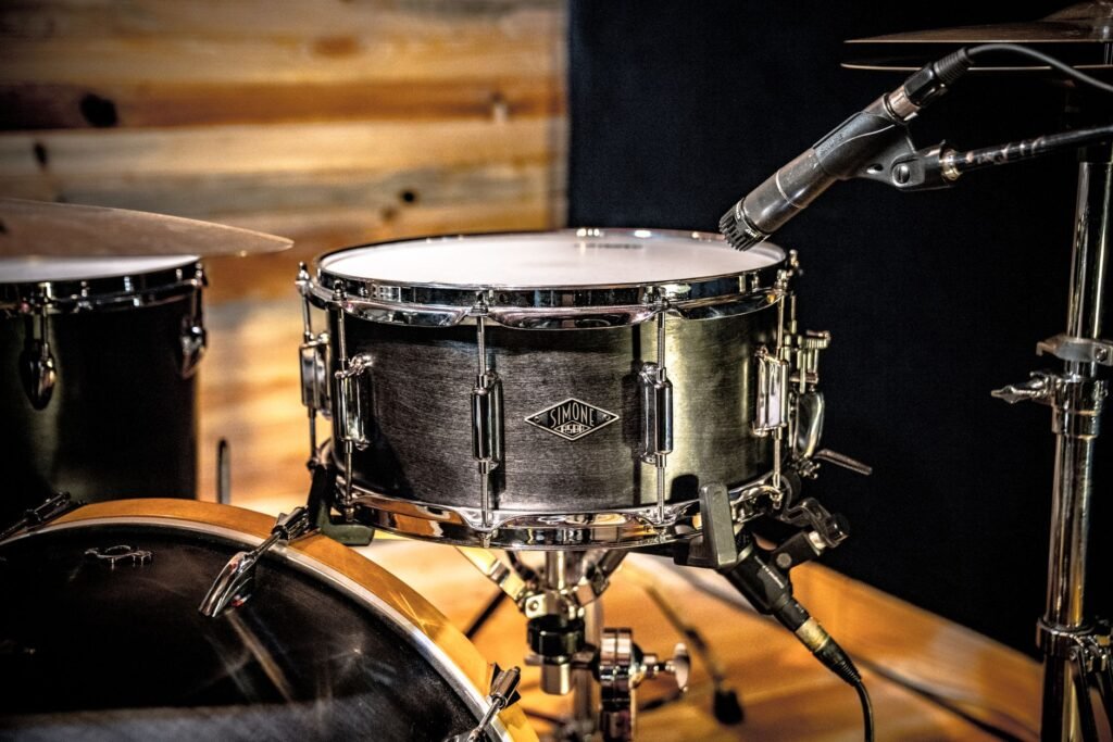 Silver snare drum on a stand with a microphone clipped nearby in a studio