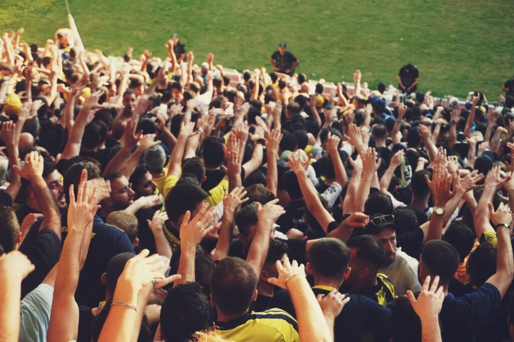 Excited crowd with raised hands at a vibrant outdoor sports event