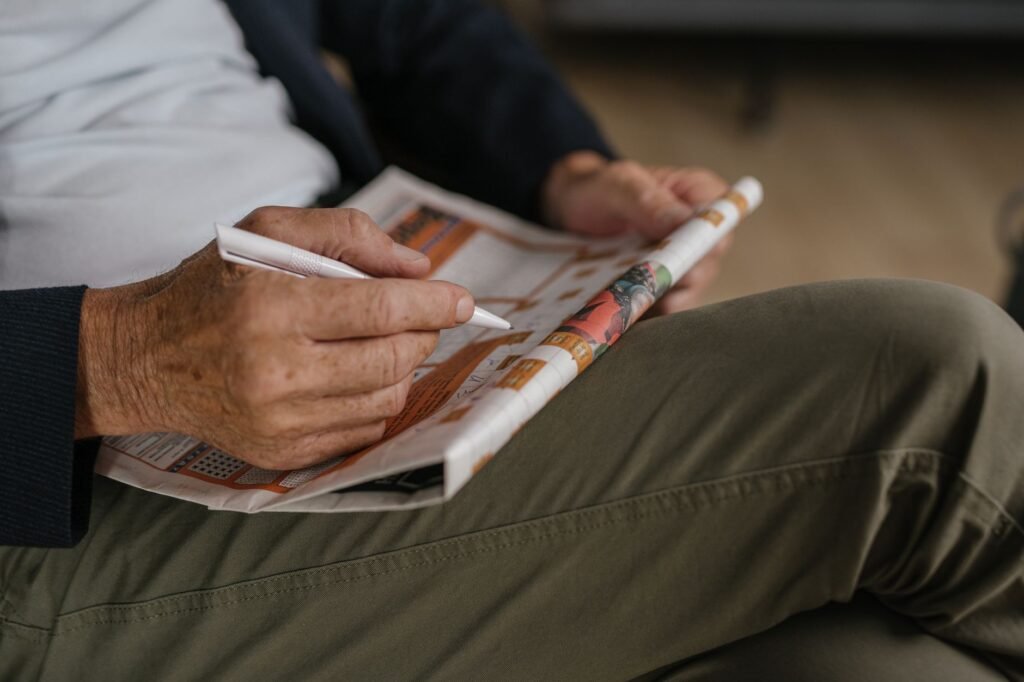 Close-up of a senior adult solving a crossword puzzle in a newspaper with a pen