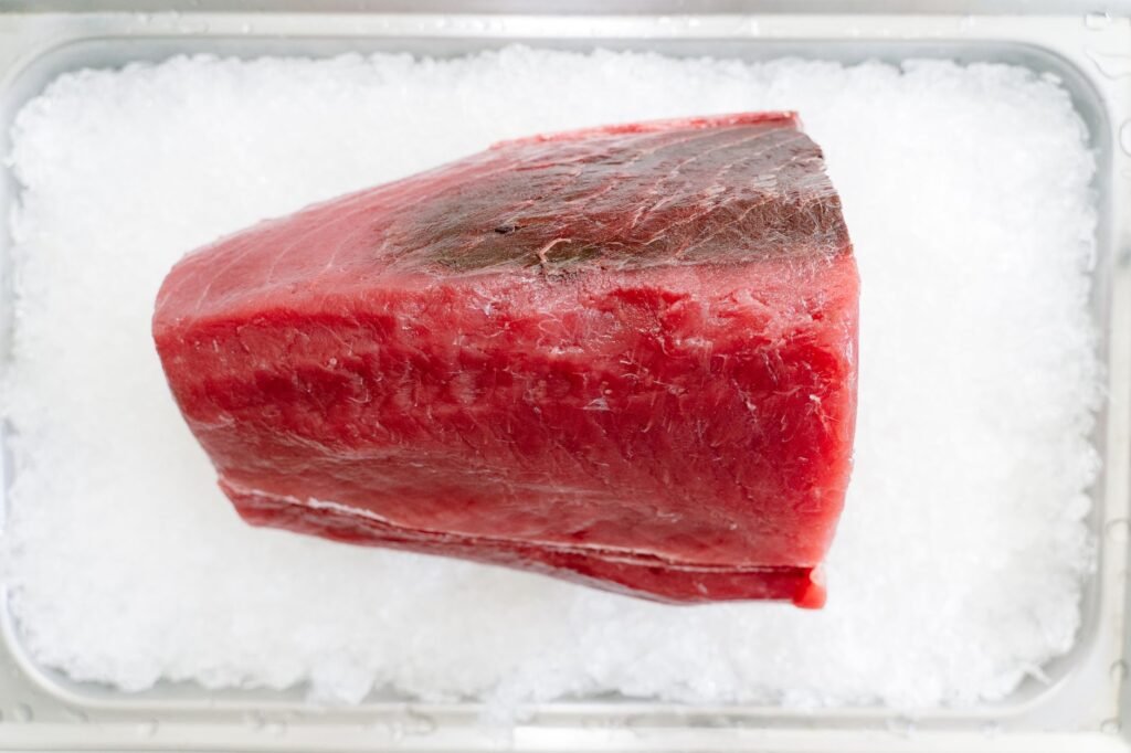 Thick deep red block of raw fish loin resting on a tray of crushed ice