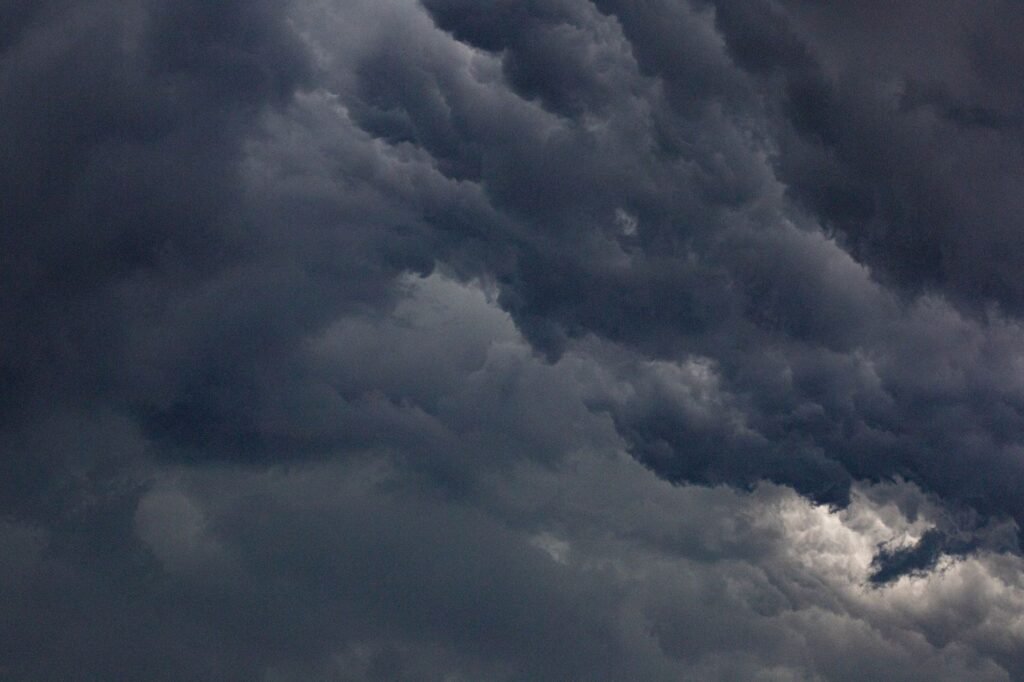 Dense dark gray storm clouds churning across the sky with a small patch of light