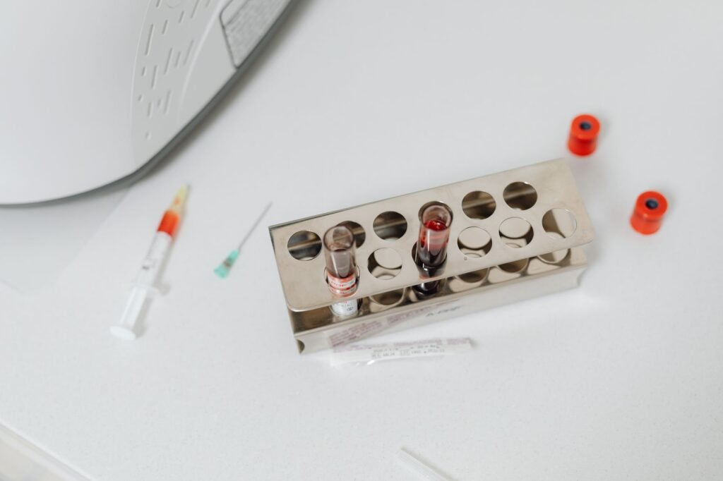 High-angle shot of lab test tubes and syringe on a white surface, perfect for science and medical themes